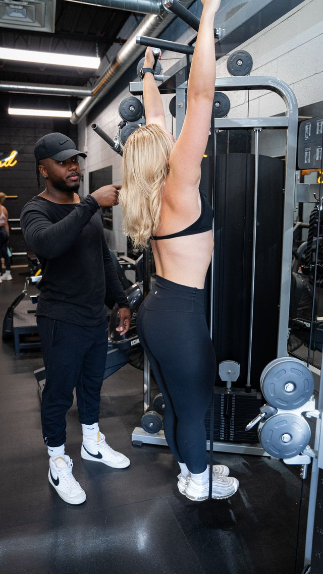 DJ coaching a client through a lat pulldown